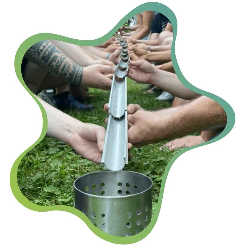 Outdoor-Kooperationsübung beim Teambuilding in Nürnberg: Team leitet Kugeln über Rinnen gemeinsam in einen Metallbehälter.